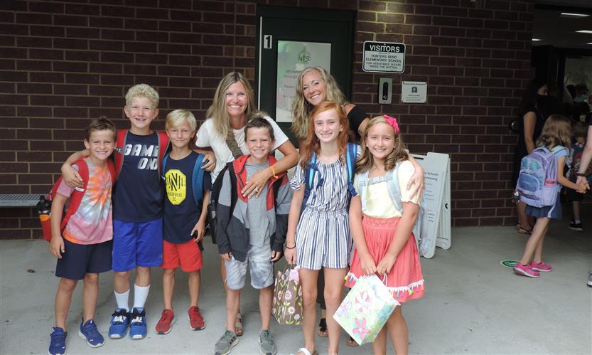 A group smiles in front of an elementary school